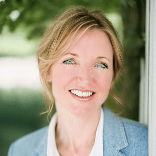 Smiling blonde woman with blue eyes wearing a denim jacket against a blurred green background.